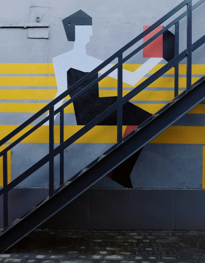 Steel staircase on a modern mural wall, showcasing artistic urban design with bold colors.